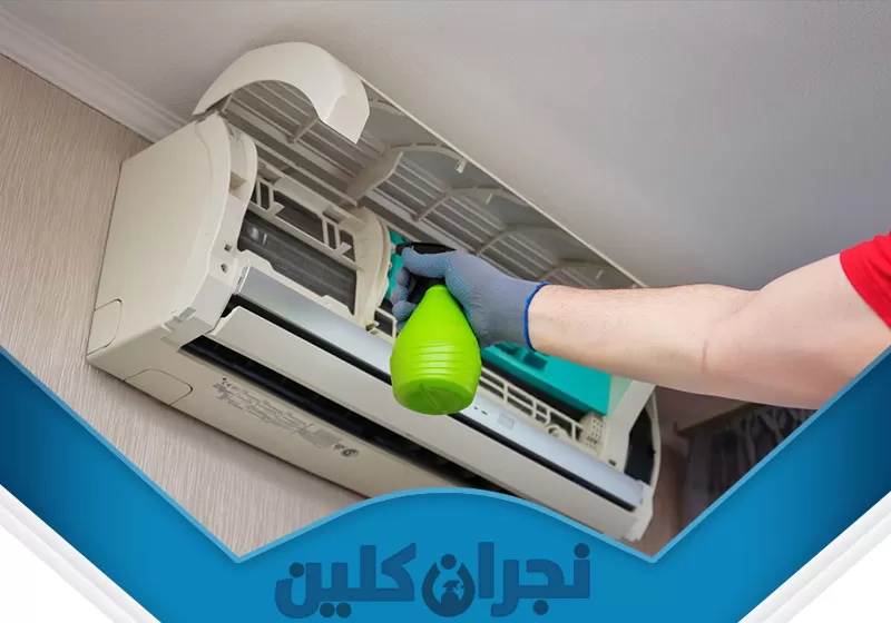 غسيل مكيف سبليت بنجران 0566353695 نجران كلين تُظهر الصورة فني شركتنا يقوم بتنظيف وحدة تكييف هواء داخلية (سبليت) مثبتة على الحائط. حيث يقوم برش سائل تنظيف من زجاجة رذاذ خضراء اللون على الأجزاء الداخلية للمكيف، والتي تبدو مفتوحة أو مكشوفة لغرض التنظيف.