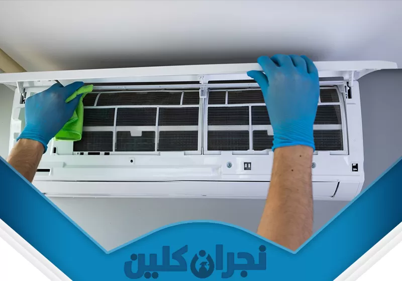 تنظيف مكيفات مركزية بنجران 0566353695 نجران كلين تُظهر الصورة عملية تنظيف مكيف هواء سبليت داخلي، حيث يقوم الفني ببتنظيف فلاتر الهواء المتسخة باستخدام قطعة قماش. يمكن ملاحظة الفرق بين الفلاتر قبل وبعد التنظيف، حيث يبدو الجزء الأعلى من الفلاتر أكثر اتساخًا ومغطى بالغبار، بينما الجزء الأسفل الذي يتم تنظيفه يبدو أنظف وأقل تراكمًا للأوساخ مما يوحي بأهمية الصيانة الدورية للمكيفات لضمان كفاءتها وجودة الهواء